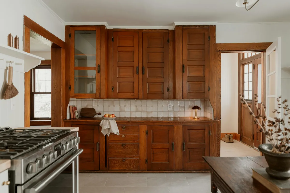 Floor to ceiling built-in wood cabinetry with glass upper doors in an older California kitchen