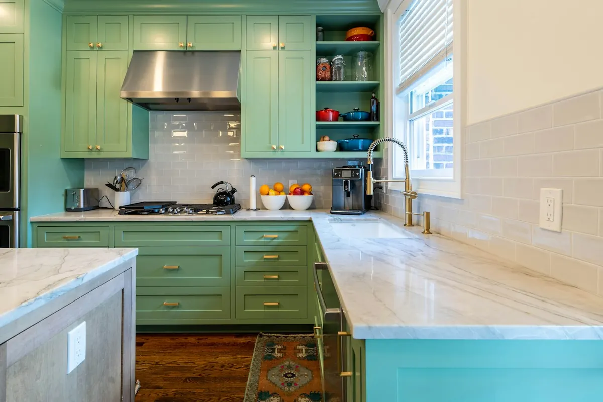Sage green custom kitchen cabinets with marble counters and brass pulls in a Lancaster CA home